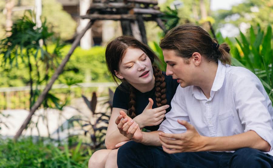Woman speaking while her partner listens attentively during a conversation outdoors