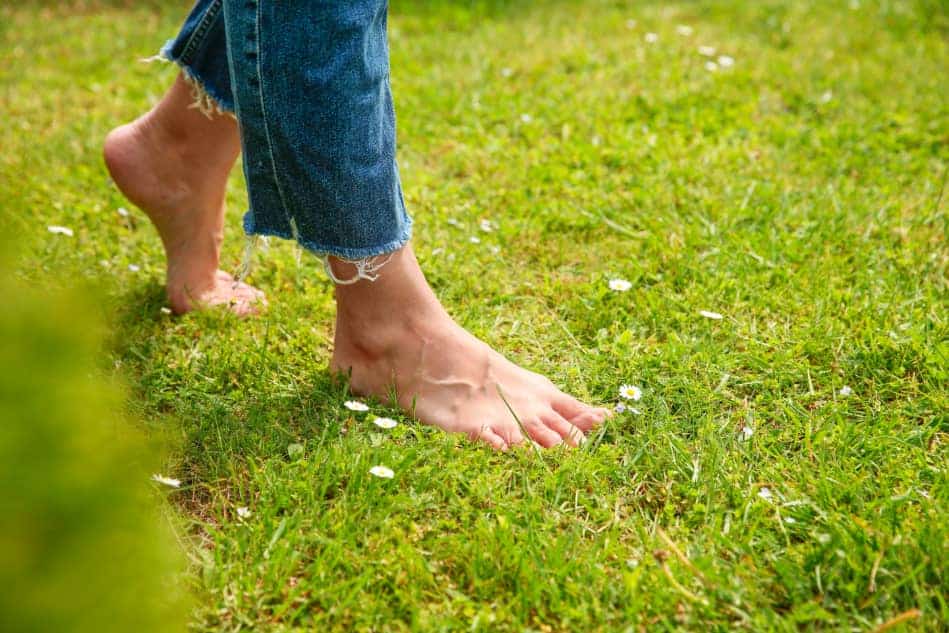 Bare feet standing on green grass, symbolizing grounding and reconnecting with the present moment.