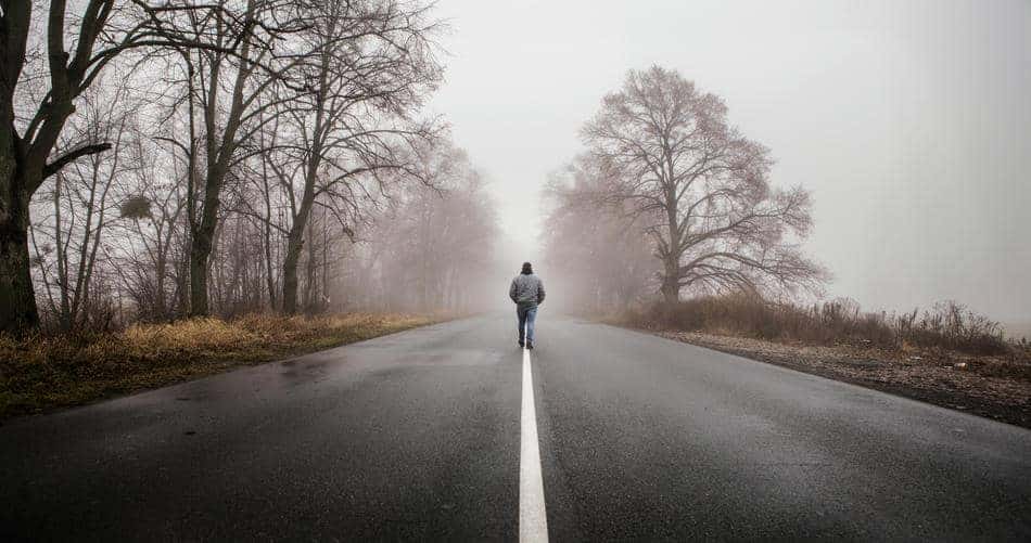 Person walking alone on a quiet road in soft fog, symbolizing direction and personal growth