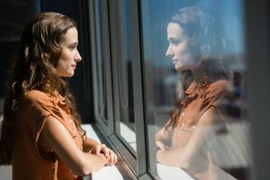 Person looking out a window in soft light, reflecting quietly during a moment of self-reflection