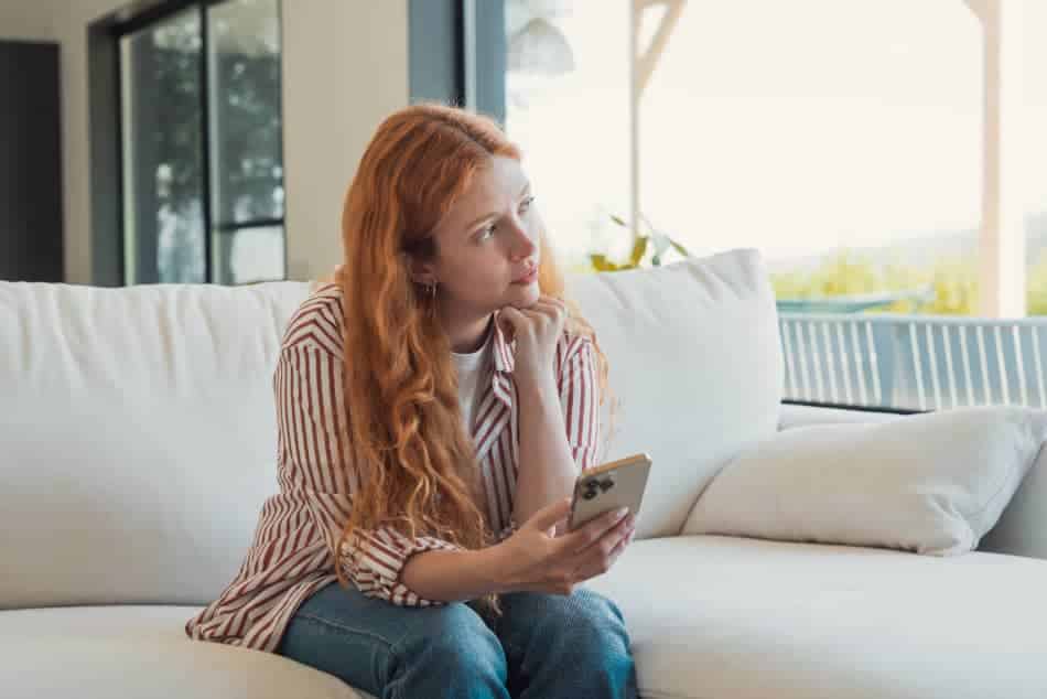 Woman holding her phone and looking away in a quiet moment of reflection