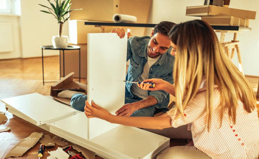 Couple assembling furniture together at home, working side by side on a shared project