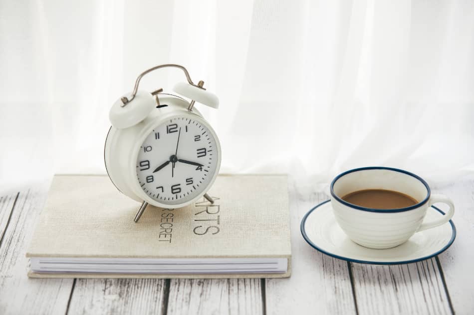 Morning coffee, notebook, and clock representing a consistent daily routine