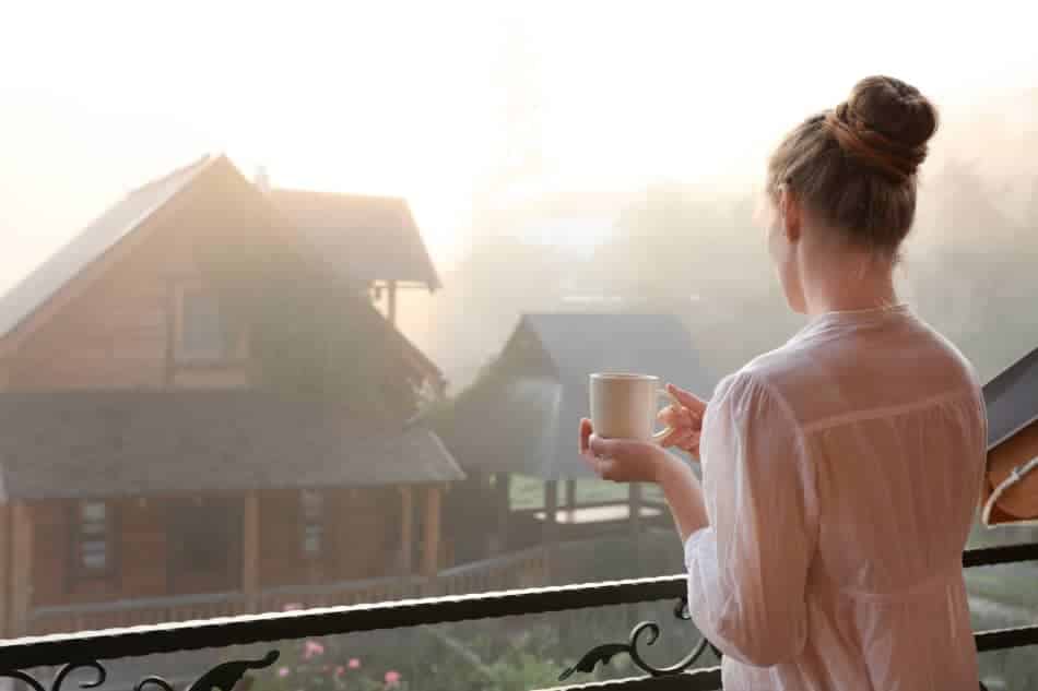 Woman holding a mug by a window during a quiet morning at home