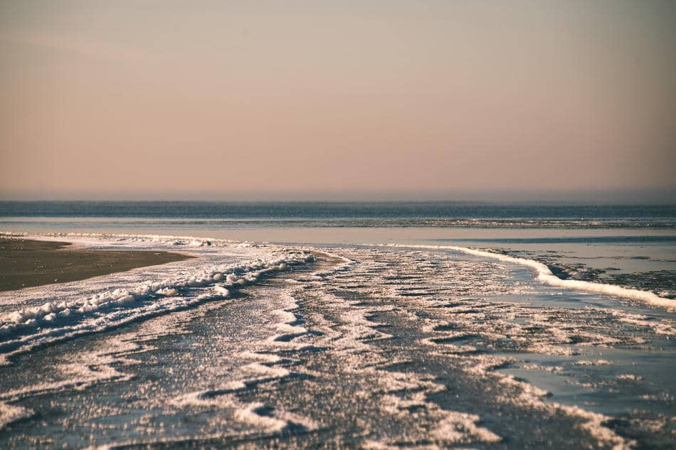 Low tide channels stretching across a quiet beach, reflecting the natural rhythm of drifting away and returning.
