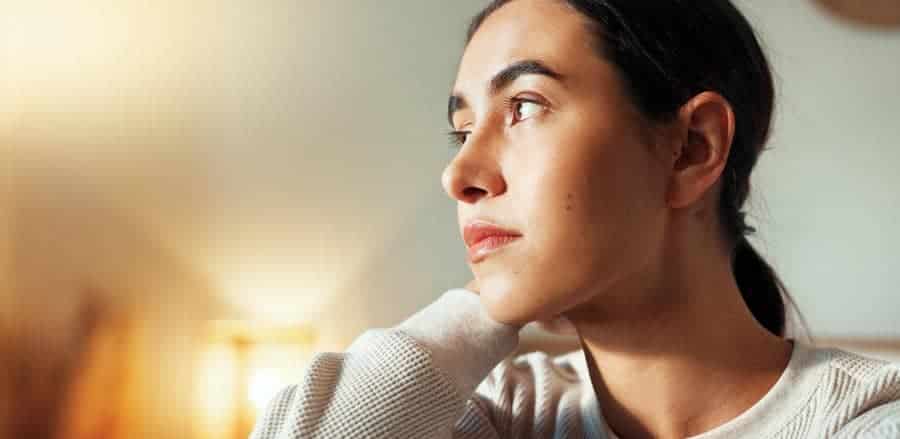 Woman looking toward soft light in a quiet moment of emotional awareness and reflection.