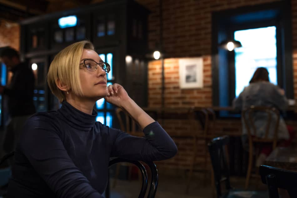 Thoughtful woman sitting alone in a café with other people in the background