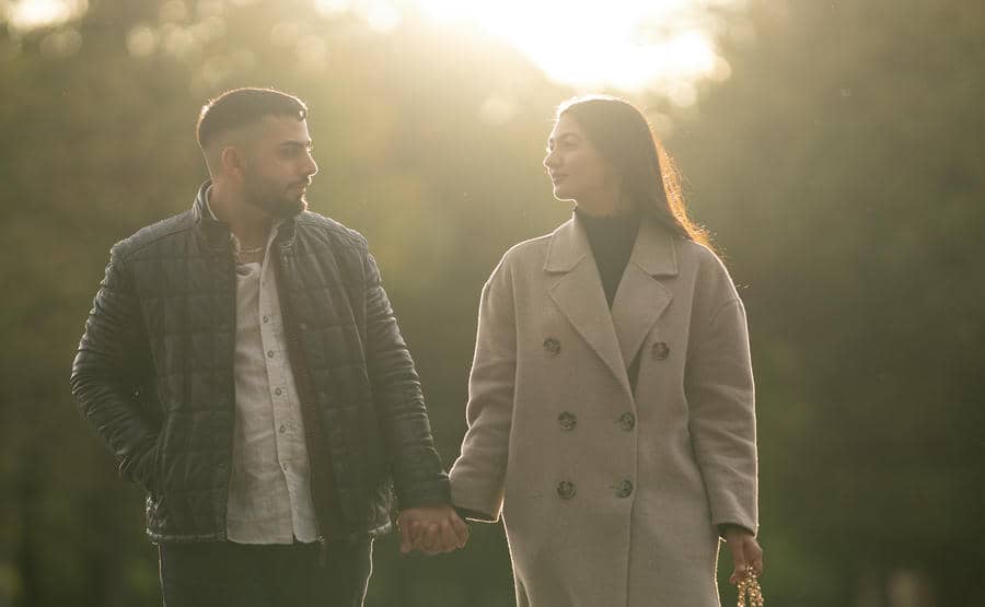 Couple walking side by side holding hands in soft golden light