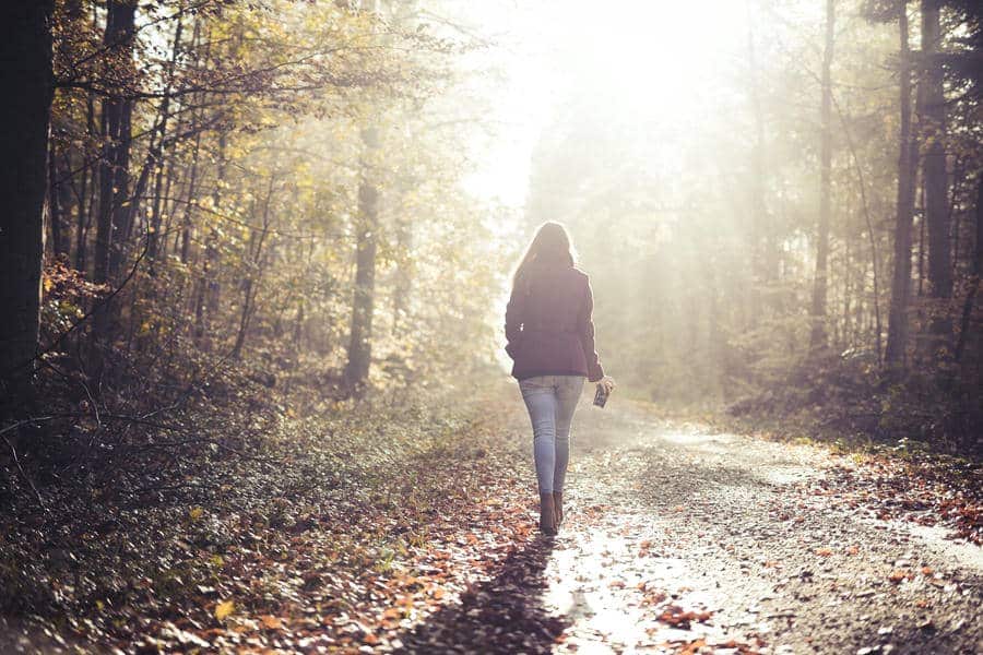 A person walking along a forest path in soft light, symbolizing a subtle shift during a difficult moment