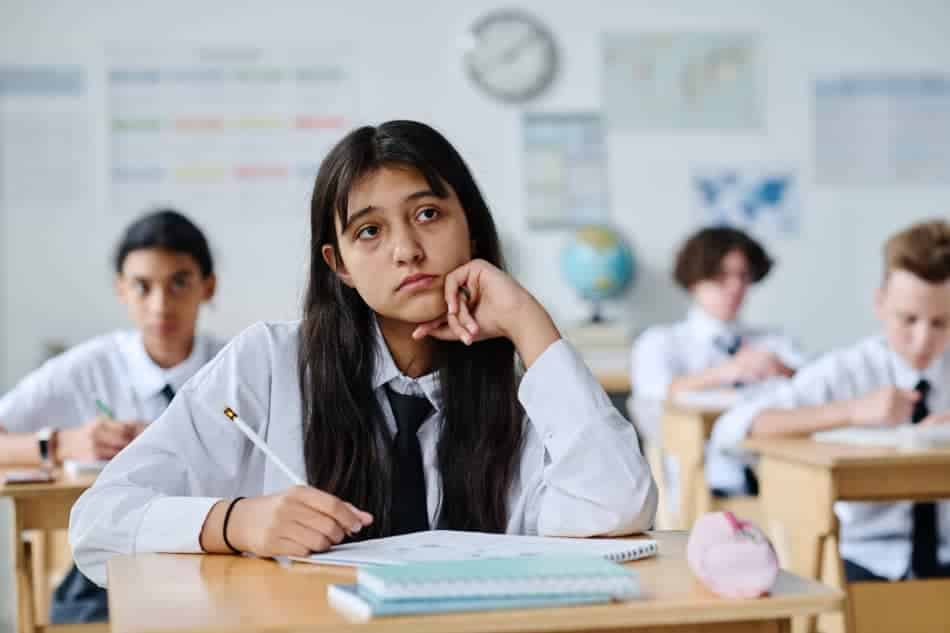 Thoughtful student sitting at a desk in a classroom