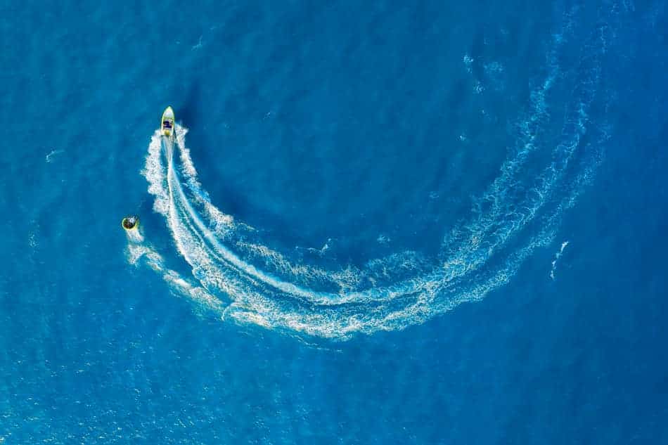 A boat changing direction and leaving a curved wake across blue water