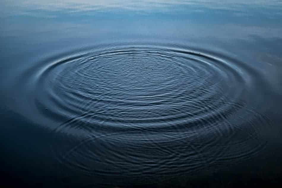 A single ripple expanding outward across still water