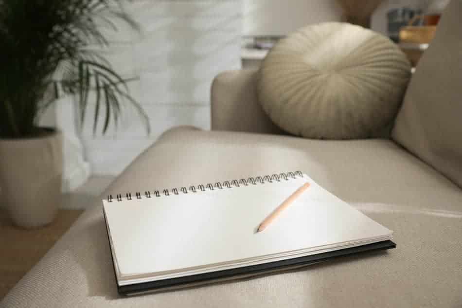 Blank journal and pencil resting on a sofa, representing the opportunity to begin again with a fresh page.