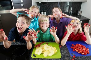 Children making a mess while cooking in a busy family kitchen during playful chaos