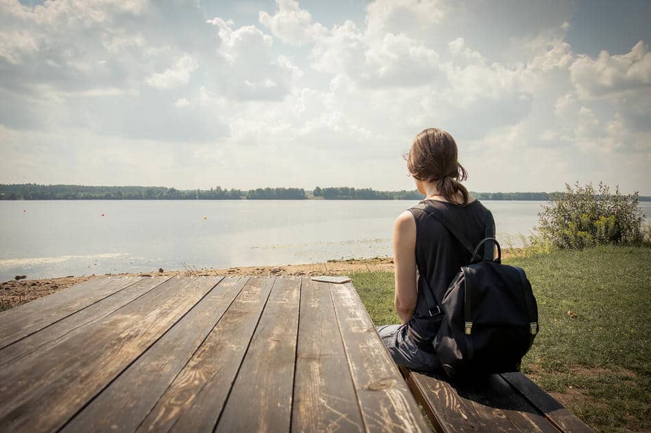 Person sitting quietly on a dock overlooking a calm lake, representing the mental freedom that comes from reducing decision fatigue.