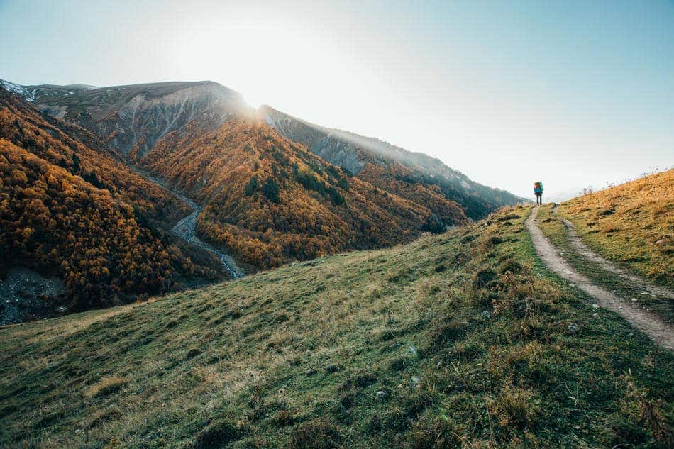 A hiker walks along a mountain ridge toward the sunlight, symbolizing clarity, direction, and intentional progress.