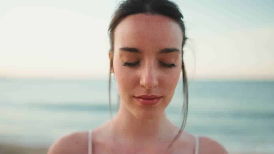 Woman with her eyes closed pausing to notice what she is feeling