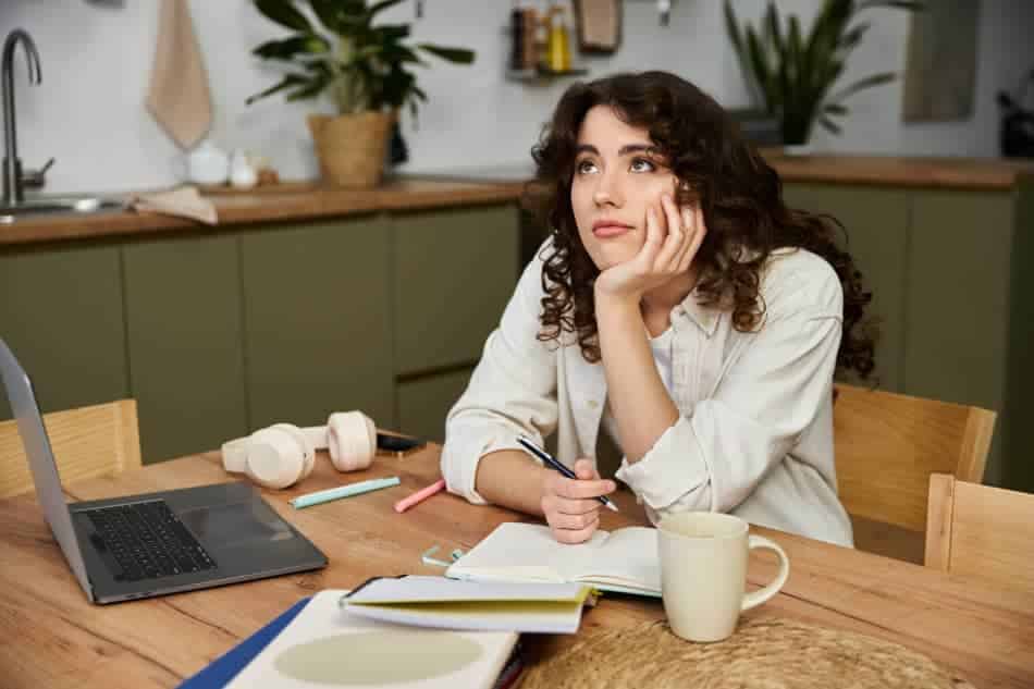 Woman at a kitchen table feeling overwhelmed by her daily routine and to-do list