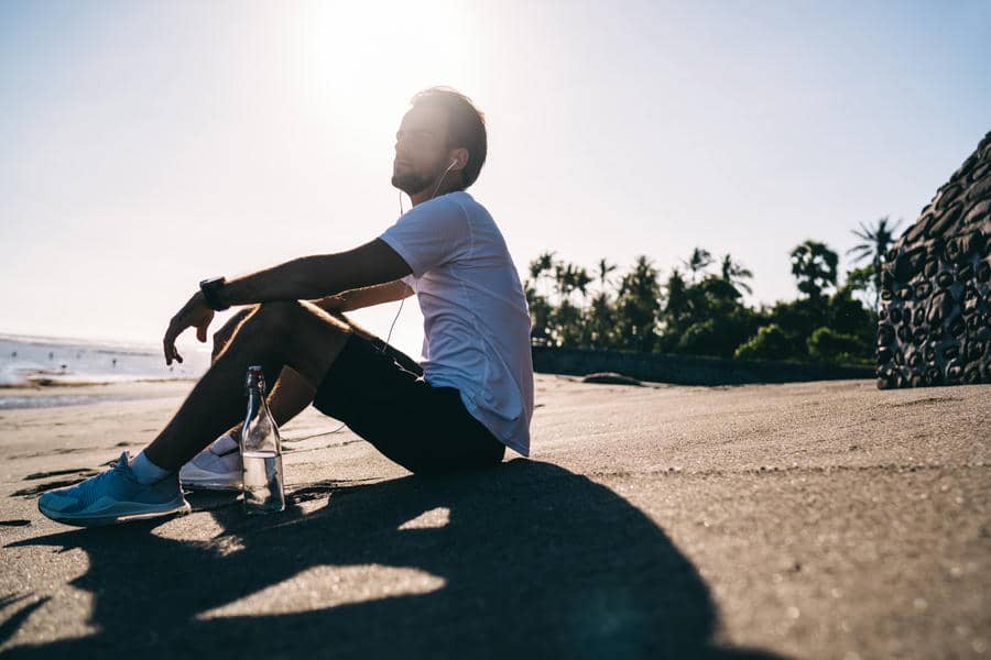 A person sitting alone outdoors in daylight, looking away thoughtfully.