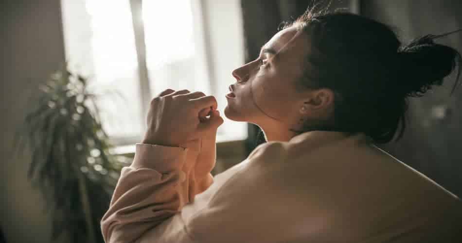 Woman sitting by a window in soft natural light, pausing in a quiet moment of self-reflection
