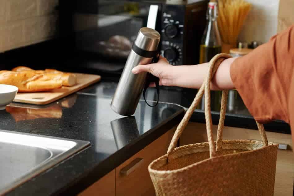 Person placing a reusable water bottle into a bag as part of a daily routine
