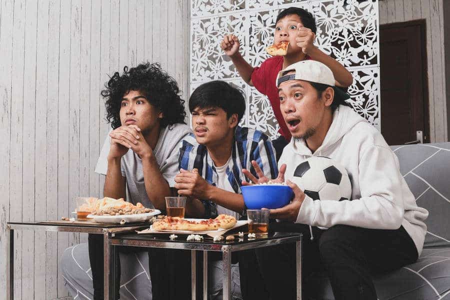 Teenage boys sitting together eating pizza and snacks during a casual gathering at home