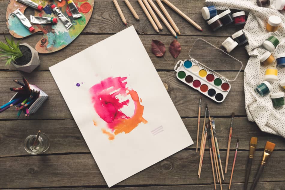 Unfinished watercolor painting surrounded by brushes and art supplies
